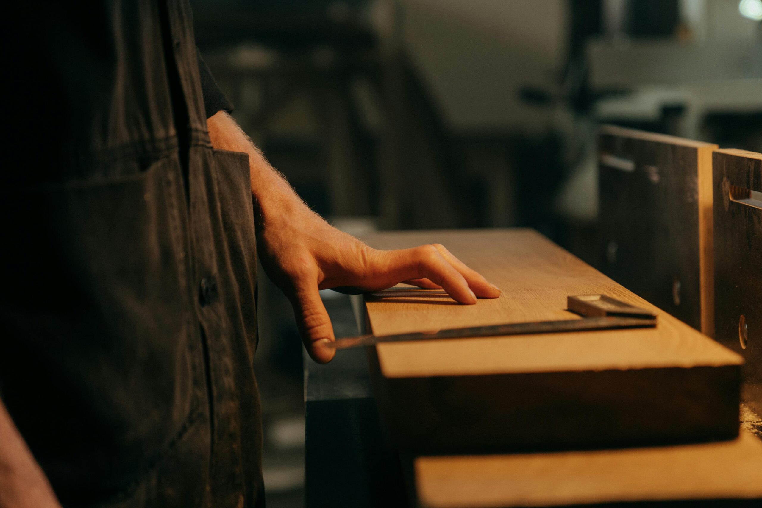 A craftsman measuring wood with precision tools in a workshop setting.