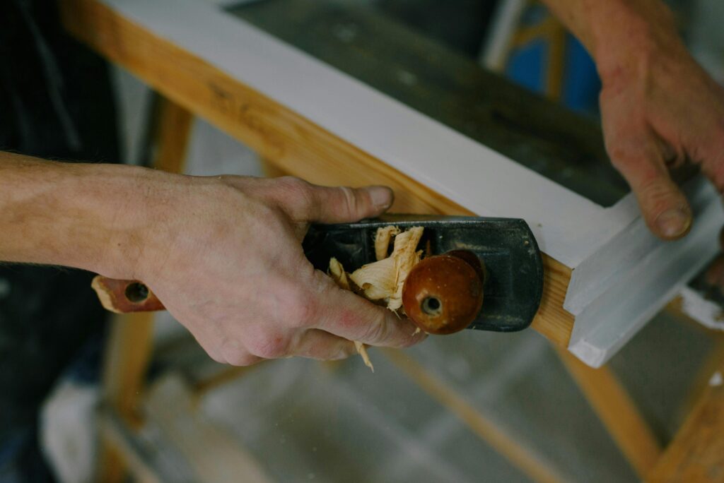 Skilled carpenter smoothing wood surface with a hand plane for fine finish.